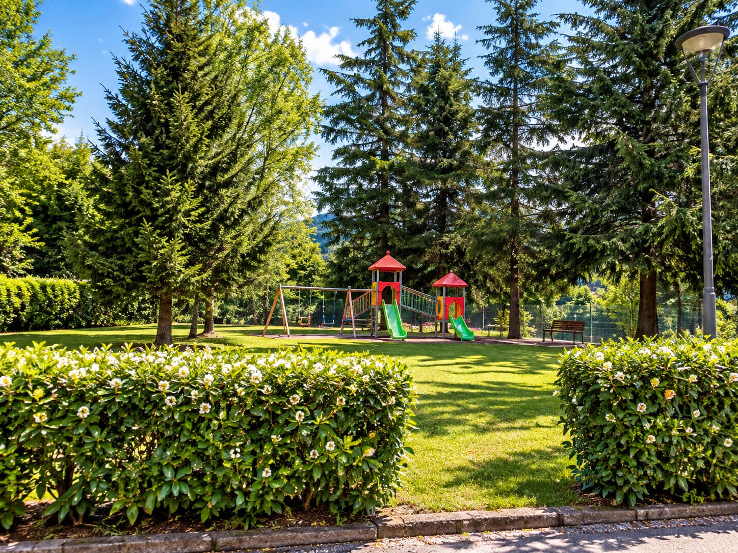 Il giardino della trattoria, con il prato, gli abeti e il parco giochi per i bambini.